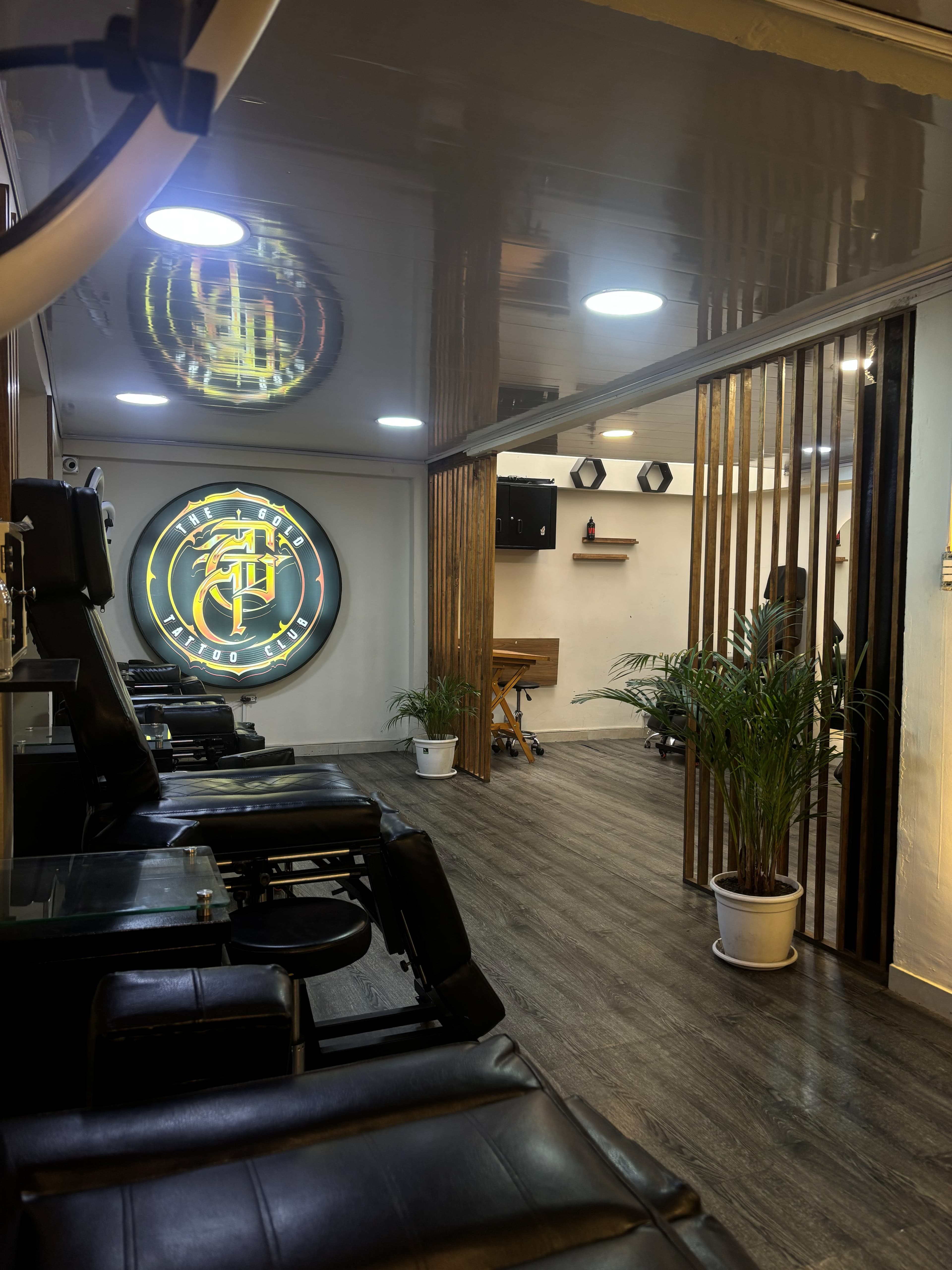 Sala principal del estudio con el logo de The Gold Tattoo Club y divisor de madera